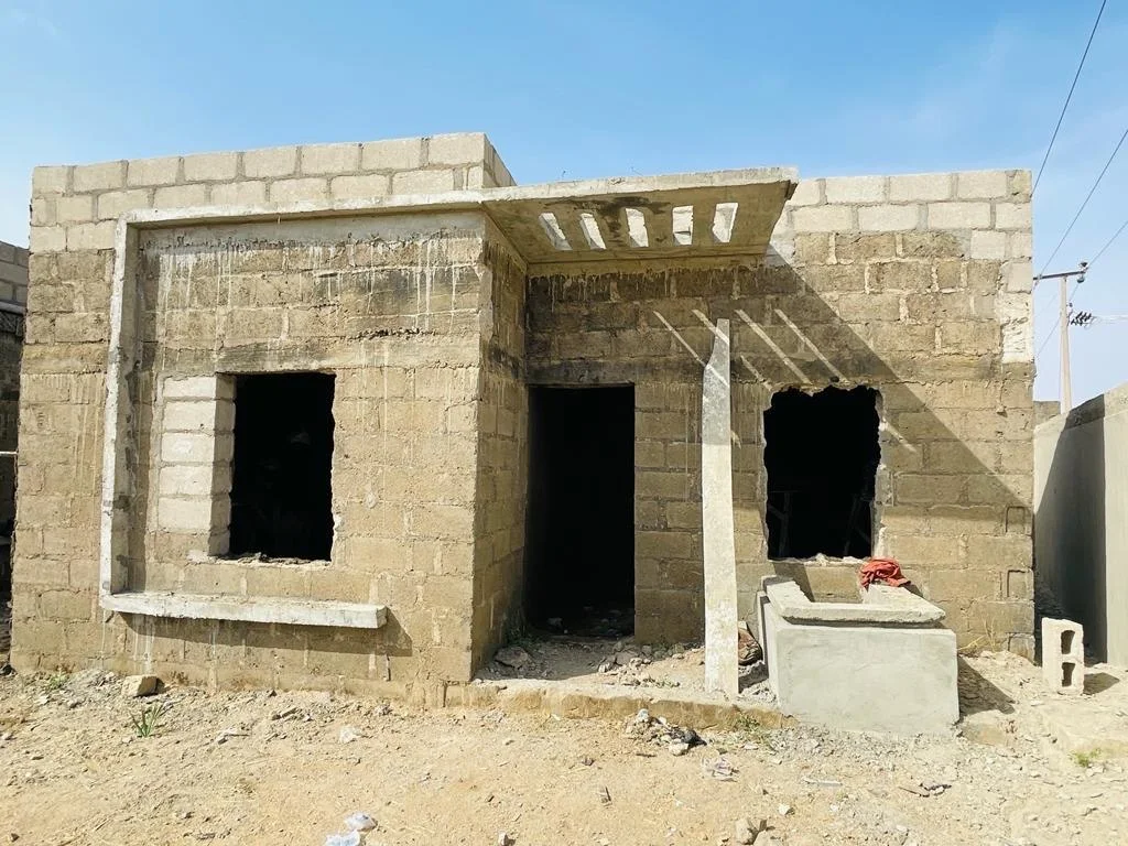 Residential unit during construction, with exposed blockwork, window openings and an unfinished entrance canopy.